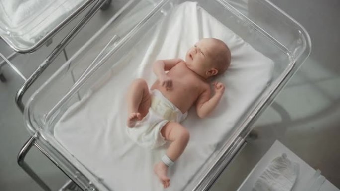 可爱的小高加索新生儿躺在托儿所的病床上。顽皮健康的小宝宝。医疗保健、生育和生育概念。自上而下的肖像