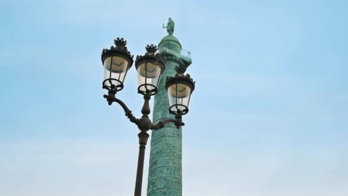 法国巴黎市中心的旺多姆广场景观。前景有灯柱的旺多姆柱，多云的天空