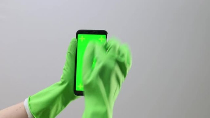 手持橡胶手套，手持手机，带chromakey屏幕，绿色显示。手指点击确定按钮，滚动，特写