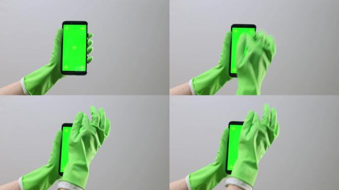手持橡胶手套，手持手机，带chromakey屏幕，绿色显示。手指点击确定按钮，滚动，特写