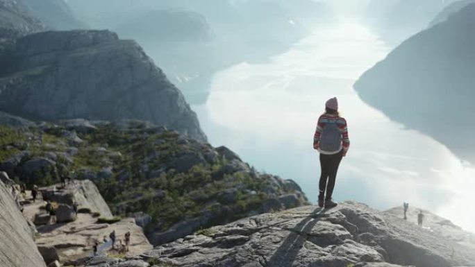 在Lysefjorden的背景下在山上徒步旅行的女人