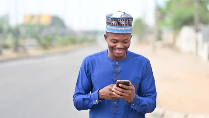 一个快乐而兴奋的非洲商人在城市中行走并使用智能手机。一个自信的年轻商人在城市背景下在线工作时赢得和庆