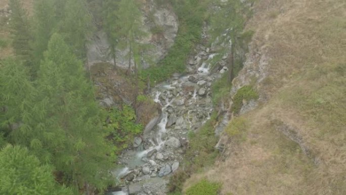 空中无人机拍摄了森林附近山丘上的一条小溪