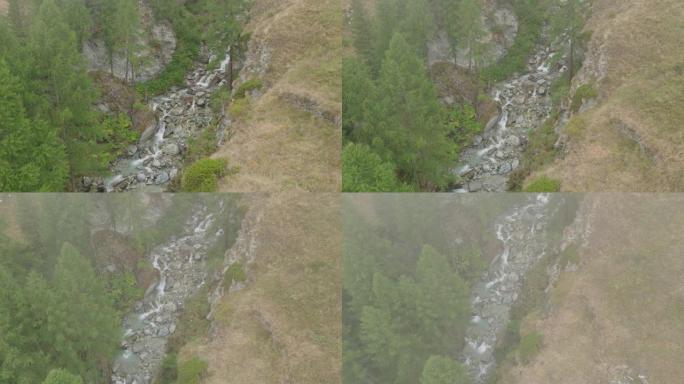 空中无人机拍摄了森林附近山丘上的一条小溪