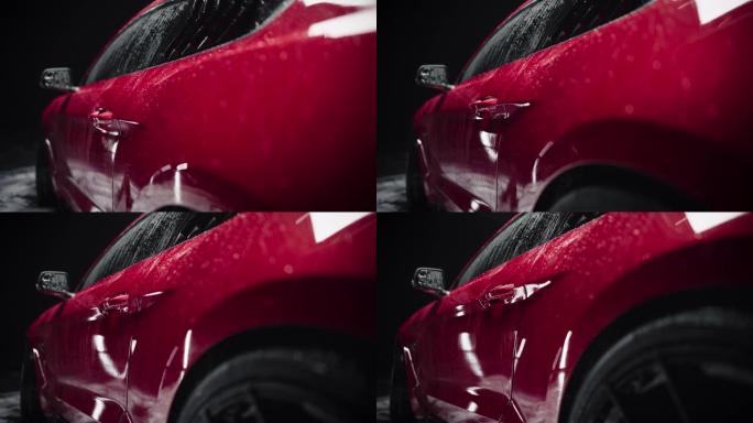 现代红色跑车的美学电影镜头。一辆光滑潮湿表面的轿跑车的特写镜头站在黑暗的细节工作室内部，在彻底洗车后