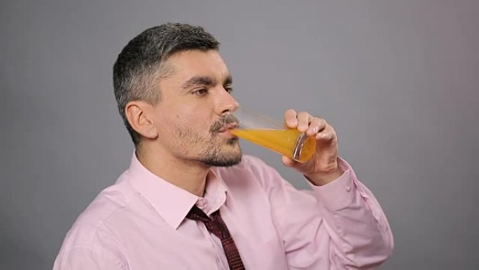 迷人的男人喝新鲜的橙汁，享受品味，健康的生活方式