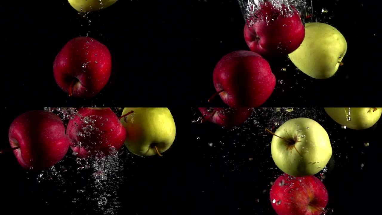 慢动作红色和黄色苹果落在黑色背景上的水中。美丽的新鲜水果在水族馆里飞溅。有机水果，健康食品，饮食，概