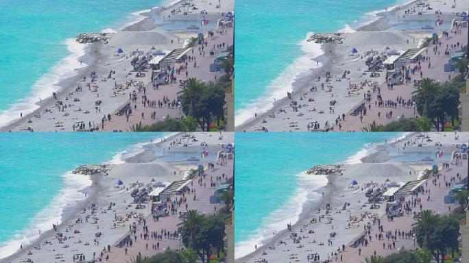 在尼斯度假城市度假，人们在路堤上晒日光浴和散步