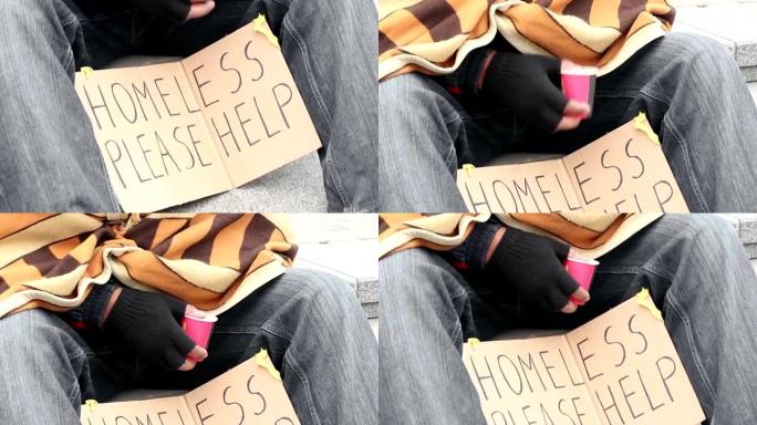 被冻住的无家可归的人被毯子覆盖，乞讨钱，拿着纸杯