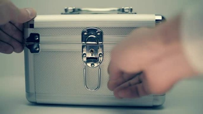 一名男子打开一个金属手提箱，从手提箱里射出一束白光