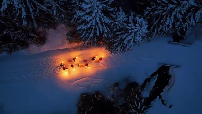 一群人在晚上用灯笼拉着雪橇在雪路上