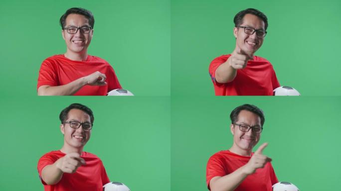 亚洲男子的特写镜头，将球放在胸前，指向前方，同时在绿屏背景上欢呼足球