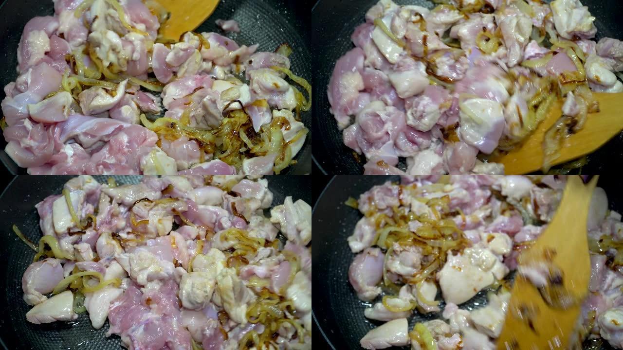 女人的手在煎锅里翻炸鸡肉。家庭主妇在厨房的煤气炉上煮洋葱炒肉