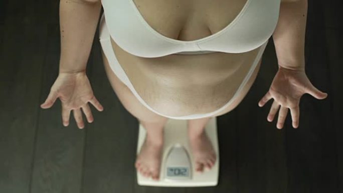 肥胖的女人站在鳞片上拼命打手势，肥胖的肚子，顶视图