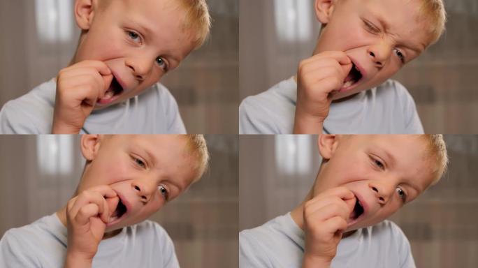 一个小男孩用手在嘴里摇动婴儿牙齿的特写镜头。