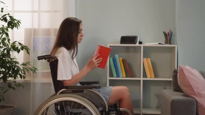 坐在轮椅上的瘫痪妇女带着红色封面的书