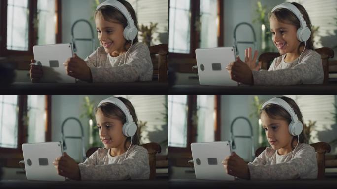 小女孩在数字平板电脑上录制视频，通过耳机收听的真实镜头。厨房里的女学生在享受周末的早晨，使用技术，进