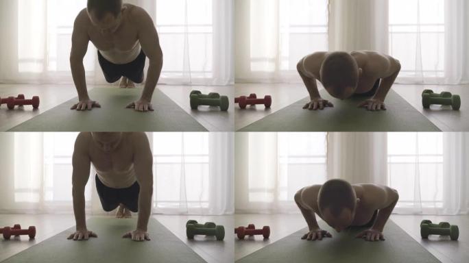 4K男人在家里锻炼，在瑜伽垫上做俯卧撑，旁边有哑铃。运动，运动，健康生活理念。