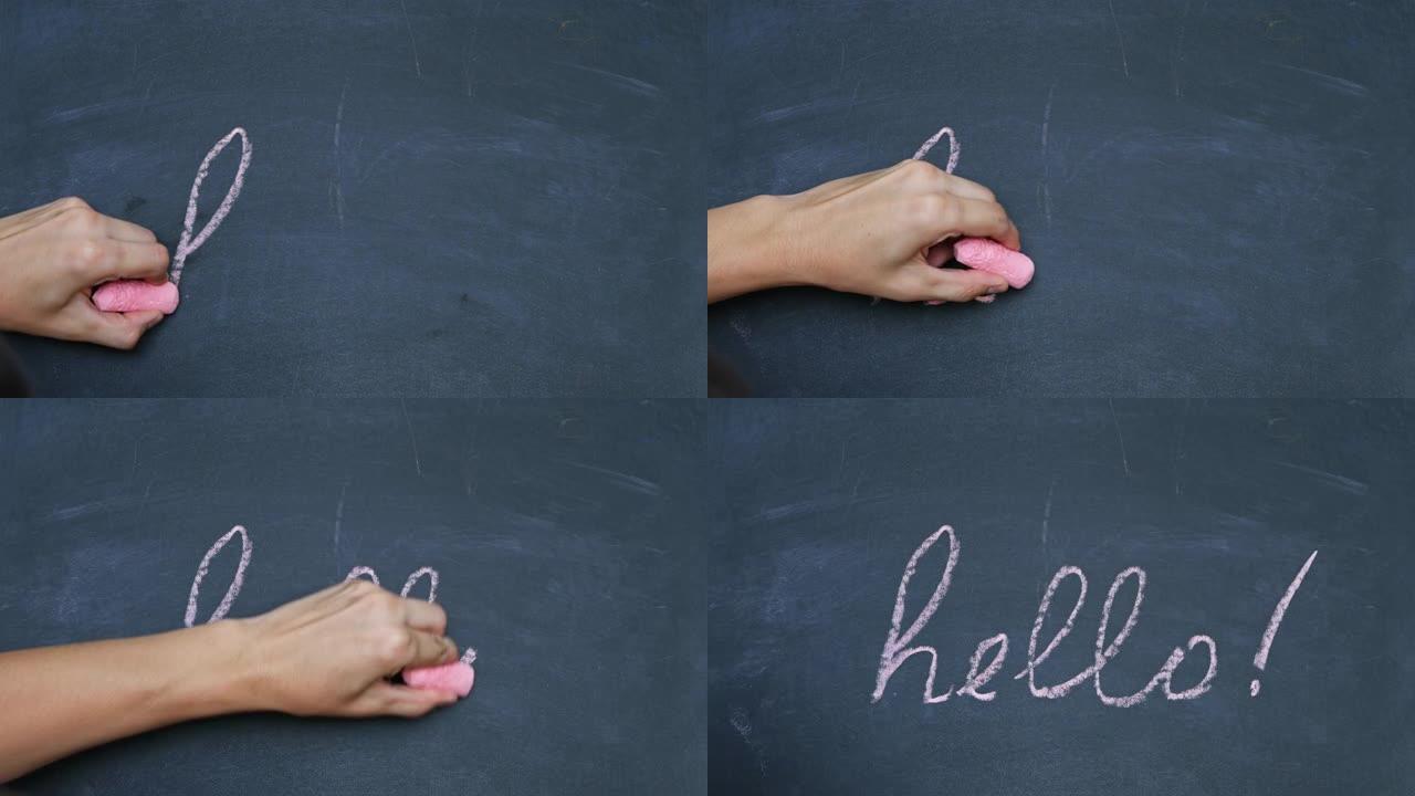 一个男人的手在学校董事会上画了一个粉笔铭文hello。用红色粉笔在黑板上手写。学校董事会上的粉笔题字