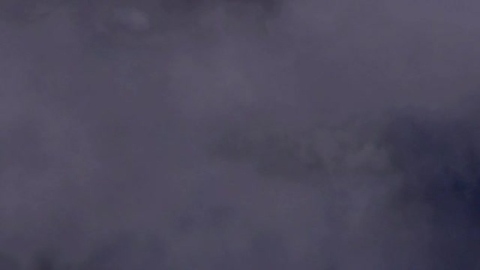 飞机飞过雷暴区，远处的闪电照亮云层。