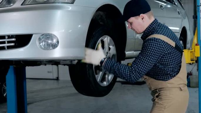 检查汽车底盘。一位年轻的制服机械师在举升的汽车服务中工作。汽车维修和保养。