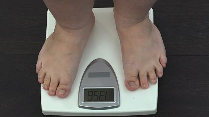 肥胖男子在家中测量体重秤，减肥训练计划，健康