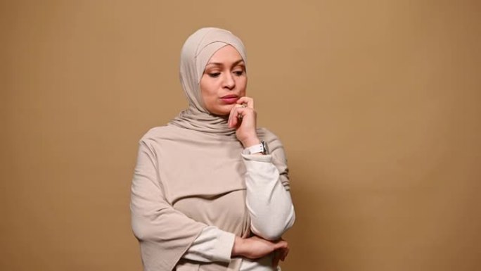 疑惑的穆斯林妇女戴着头巾，思考问题，在寻找解决方案时指向上面