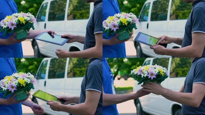 男子在平板电脑上签名，并从送货员那里收到鲜花礼物