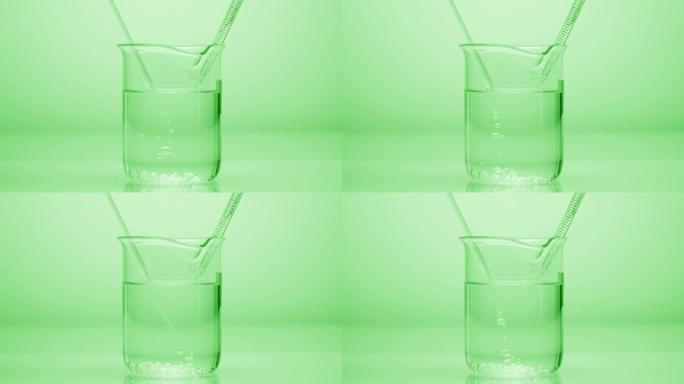 滴管滴落在绿色背景上的烧杯中的液体