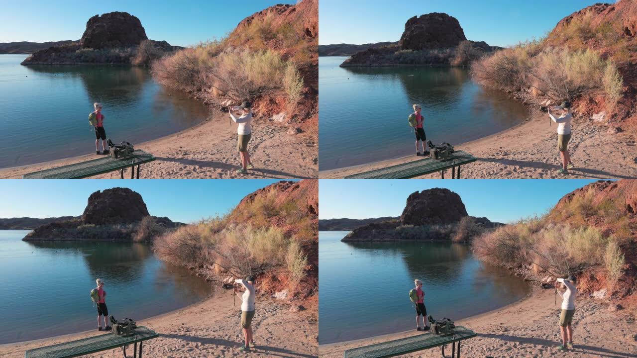 女徒步旅行者在空荡荡的湖畔拍照