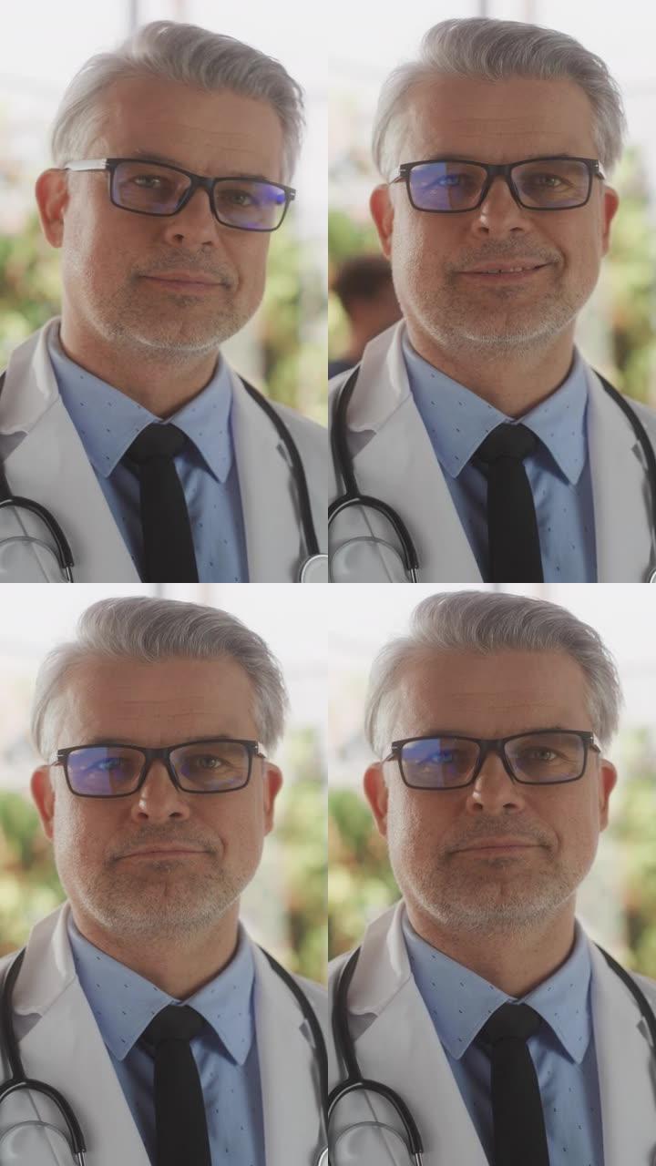 竖屏:中年医疗保健专业人员摆姿势，微笑着看着镜头。戴眼镜、穿白大褂的白种人门诊医生在医院办公室工作