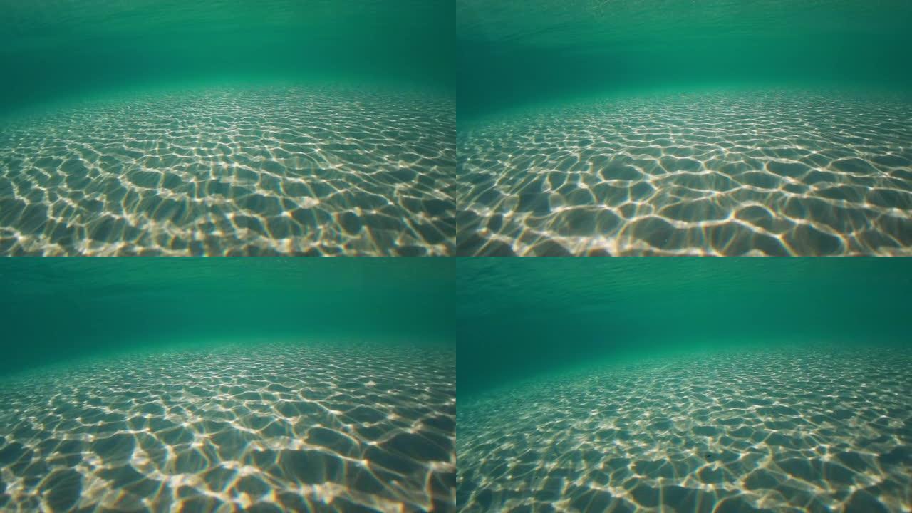 阳光穿透海水，带着柔和的波浪和运动，在沙滩上形成的水下光纹