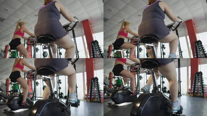 女人在健身房的固定自行车上踩着粗壮的腿，减肥