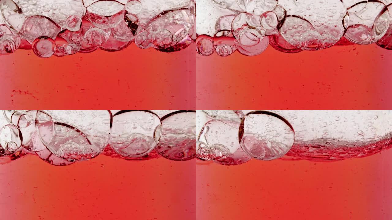 移动的红色油的慢动作，水中的气泡在浅白色背景上上升。带有气泡的透明化妆品凝胶液。宏观拍摄。