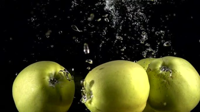 慢动作黄色苹果落在黑色背景下的水下。美丽的新鲜水果在水族馆里飞溅。有机水果，健康食品，饮食，概念。以