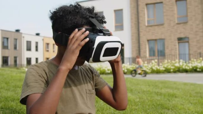 年轻的黑人男孩在户外尝试VR耳机