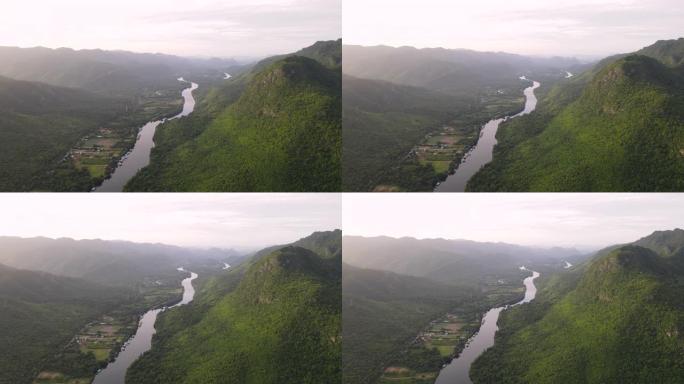 沿河的筏屋的绿色自然鸟瞰图，在热带绿色森林和宁静的河流上飞翔，早晨的阳光