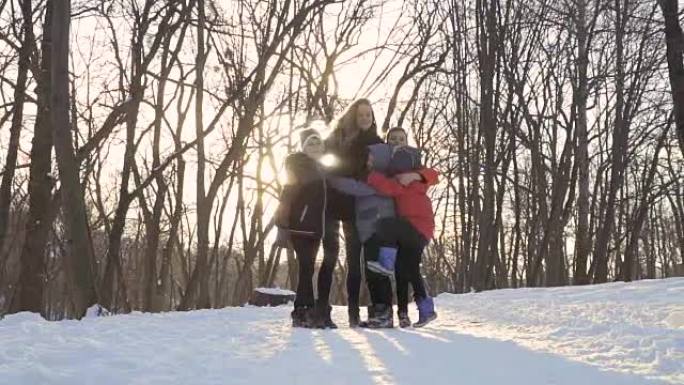 年轻的母亲在冬季公园与儿子们拥抱