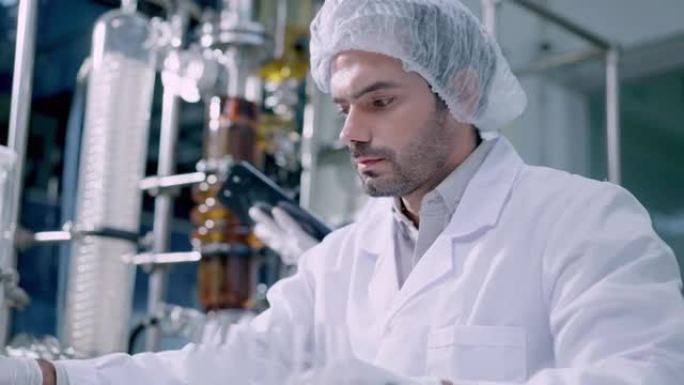 英俊的科学男子在防护手套，发网和实验室外套制作临床实验中，用黄色流体拿着试管，混合试剂研究实验室提取