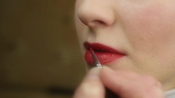 化妆工作室涂红色唇膏的过程。美丽的女性