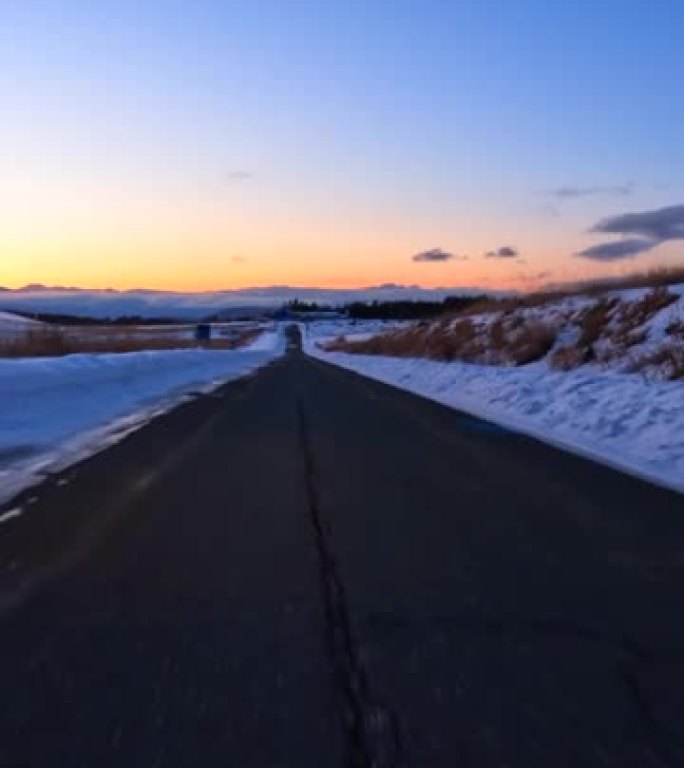 黄昏时在雪山路上行驶。