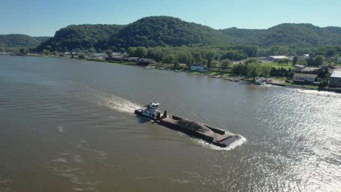 一艘拖船在密西西比河上向北推了一艘泥土驳船，经过爱荷华州兰辛。