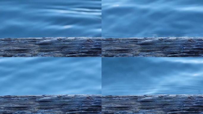 从码头流到湿板下的蓝色河水。特写。水和湿板。