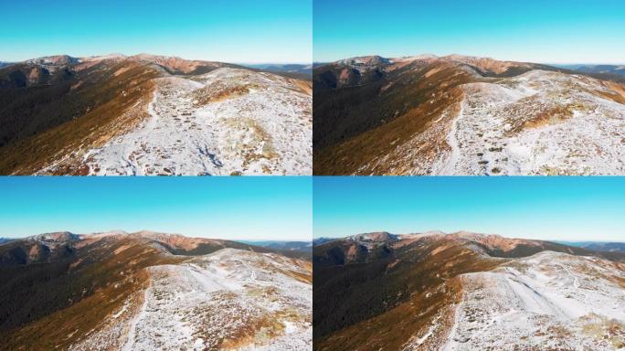 蓝天日白雪覆盖的山脉的空中无人机视图