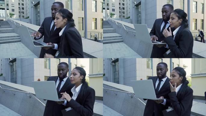 男人和女人看着大楼外的笔记本电脑，律师，全新的证据