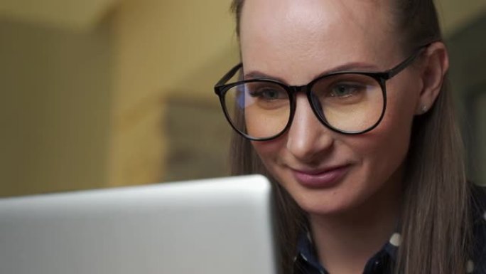 一位年轻的女商人的肖像，戴着眼镜在办公室里用电脑工作。技术、商业和金融、经济学、管理学、成功的概念