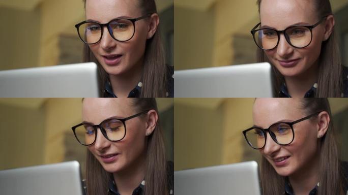 一位年轻的女商人的肖像，戴着眼镜在办公室里用电脑工作。技术、商业和金融、经济学、管理学、成功的概念