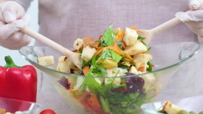 Be H3althy女人混合蔬菜沙拉的成分慢动作视频与掉落的生菜混合在玻璃板胡萝卜芝麻菜菠菜西红柿油