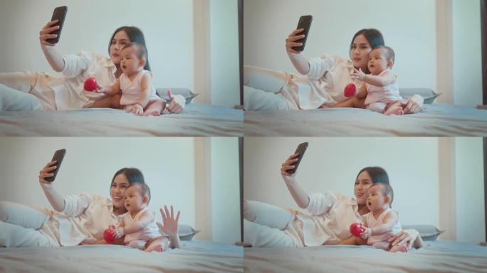 快乐妈妈和女婴看着相机在家打视频电话，家庭概念