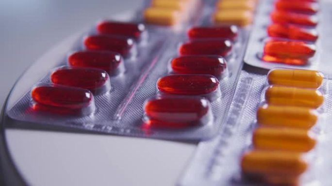 特写药品水泡用橘红色胶囊躺在桌子上，制药公司从事生产具有活性成分的新药，广告